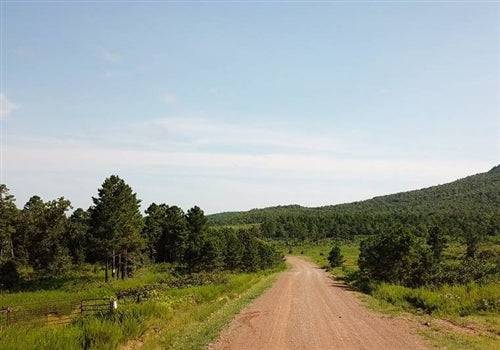 Aerial view of Tyler Stone Ranch Lot 10, a 4.94-acre property in Le Flore County, Oklahoma, with open land and surrounding trees.