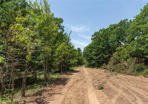 Aerial view of Oklahoma McIntosh County Timber Ridge Lot 38, a 2.66-acre wooded property with open land and surrounding trees.