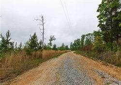 Aerial view of Tennessee Benton County Red Barn Ranch lot 61 with open land, red barn, and a stream on the property.