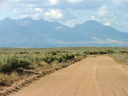 Aerial view of 10-acre Colorado San Luis Valley land in Costilla County, with open fields and mountain background, offered by Onlinelandsales.